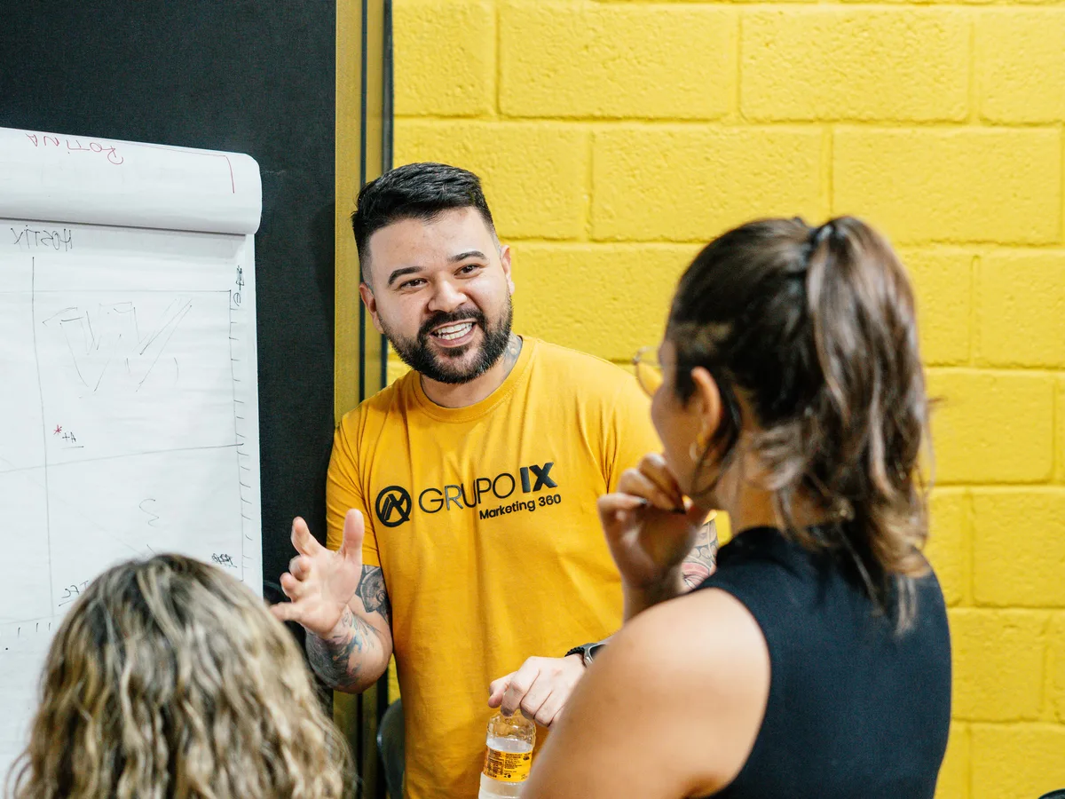 Felipe Jacoto diante do flipchart discutindo com duas pessoas